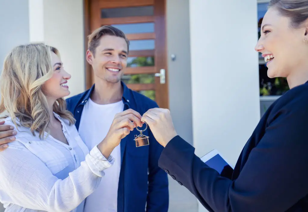 A landlord handing over a set of keys to her new tenants.
