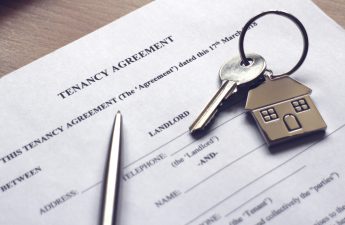 A house key resting on paperwork titled, "Tenant Agreement." RentPrep tenant screening