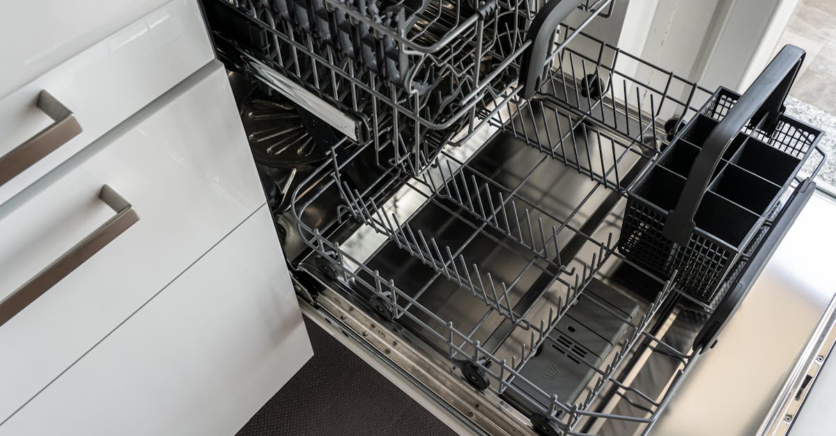A clean and empty stainless steel dishwasher open in a modern kitchen setting.